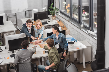 Wall Mural - cheerful multicultural business team making stack of hands at modern office