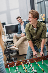 Wall Mural - cheerful office workers playing in table soccer at modern office