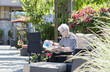 Elderly Woman Sitting Outside with Wheelchair at a Retirement Home Garden Reading the Paper
