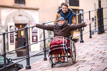 Senior father in wheelchair and young son on a walk.