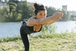 © Arno Images - Young Japanese woman practicing yoga exercises near a river in a summer day in the city