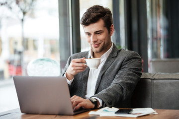 Canvas Print - Smiling business man sitting by the table in cafe