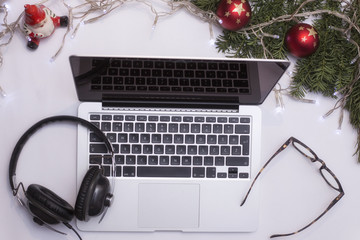 Top view office table desk. Workspace with laptop and christmas decorations on white background xmas lights bokeh glasses phones tea