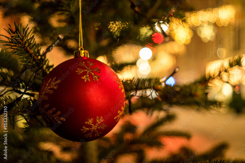 Stock-Foto „Weihnachtskugel auf Baum mit Beleuchtung im Hintergrund“