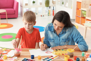 Canvas Print - Cute boy with mother painting at table in room