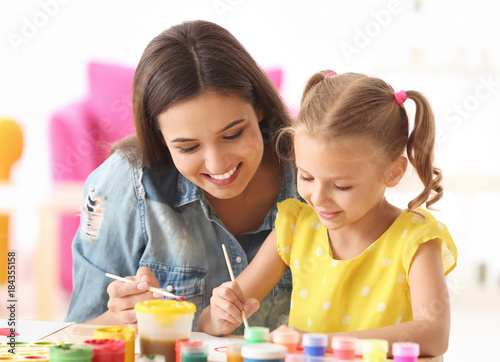 Fotografía Cute girl with mother painting at table indoors