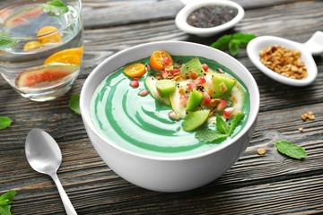 Poster - Bowl with green spirulina smoothie on table. Healthy vegan food concept