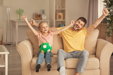 Wall Mural - Cute girl and her father watching football match on TV