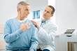 © zinkevych - Professional osteopath. Smart handsome male doctor sitting behind his patient and wearing stethoscope while examining him