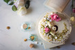 Chiffon cake con cioccolato bianco decorata con pistacchi, meringhe e petali di rosa su tavolo di marmo