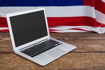 Wall Mural - Laptop and American flag on wooden table