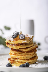 Wall Mural - Pile of pancakes with blueberries on the top, maple leaf syrup is pouring on it.