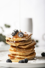 Wall Mural - Pile of pancakes with blueberries on the top, maple leaf syrup is pouring on it.