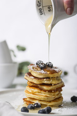 Wall Mural - Pile of pancakes with blueberries on the top, maple leaf syrup is pouring on it. 
