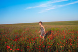 Fototapeta Kuchnia - Little girl runs across the field of flowering poppies