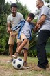 © wavebreak3 - Low angle view of family playing soccer in yard