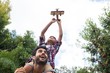 © wavebreak3 - Low angle view of father carrying son playing with airplane