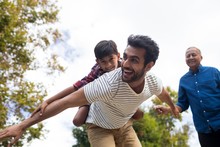Happy Grandfather Looking At Man Giving Piggy Backing To Son