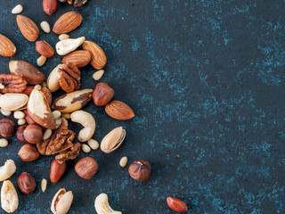 Wall Mural - Background of nuts - cashew, pecan, pine nuts, hazelnuts - on dark blue background with copy space. Top view or flat lay