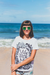 Wall Mural - Beautiful young woman in sunglasses posing on the beach of a tropical island of Bali, Indonesia.