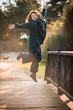 © Lambros Kazan - Atractive Happy Woman Jumping Up by a Wooden Old Bridge in the Forest, Enjoying Life
