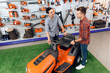 © VadimGuzhva - A consultant in a garden tools store shows a customer a lawn mower.