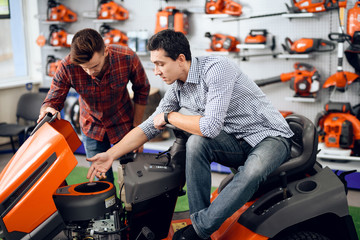 A consultant in a garden tools store shows a customer a lawn mower.