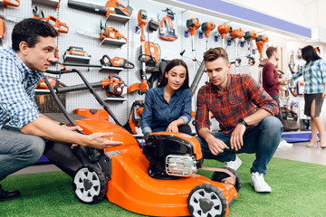 Wall Mural - The seller in the store shows the customers a mowing machine.