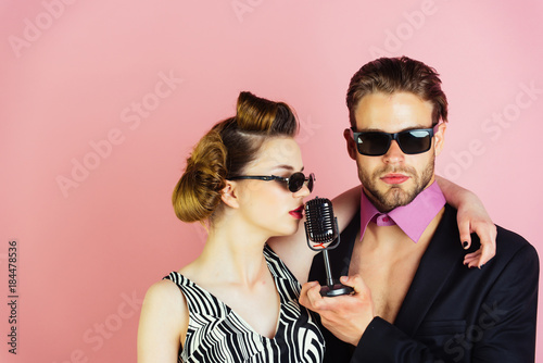Fototapeta na szkło Couple in love in glasses sing in microphone.