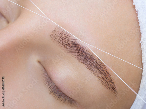 Fotografía The make-up artist plucks her eyebrows with a thread close-up