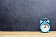 Time is running out concept with classic alarm clock isolated on wooden table and blackboard background