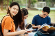 © jumlongch - A group of young or teen Asian student in university smiling and reading the book and look at the tablet or laptop computer in summer holiday.
