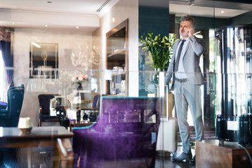 Wall Mural - Mature businessman with smartphone in a hotel lounge.