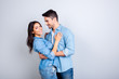 © deagreez - Portrait of sweet hispanic cute lovers, bearded man hugging woman and looking at her, pretty woman looking at camera over grey background