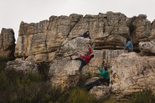 Friends Assisting Man In Rock Climbing