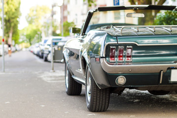 Close up back view of black old vintage car parked on a street in city or automobile back side with back light. Back side of vintage car concept.