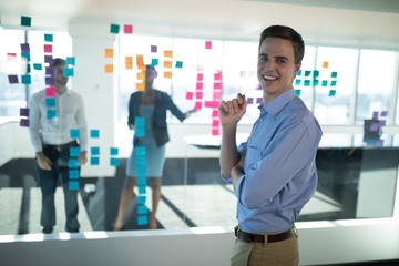 Wall Mural - Male executive standing in office with colleagues in background