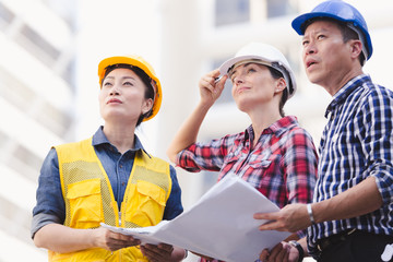 Engineers man and woman working on plan building construction in city