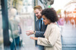 © Mediteraneo - Young happy mixed race couple looking at a window of a clothing store