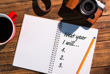 Top View of new years resolution written  on notepad with pencil and vintage  photo camera on side