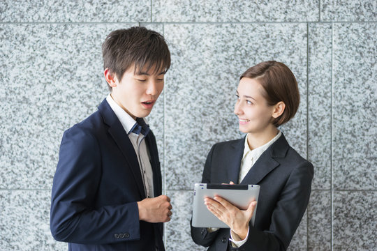 タブレットPCでミーティングをする外国人の男女（国際化イメージ）