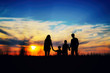 © Lazy_Bear - Father, mother, and children hold hands on a sunset background.