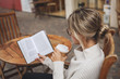 © xo4uphoto - Woman reading a paper book with a cup of coffee