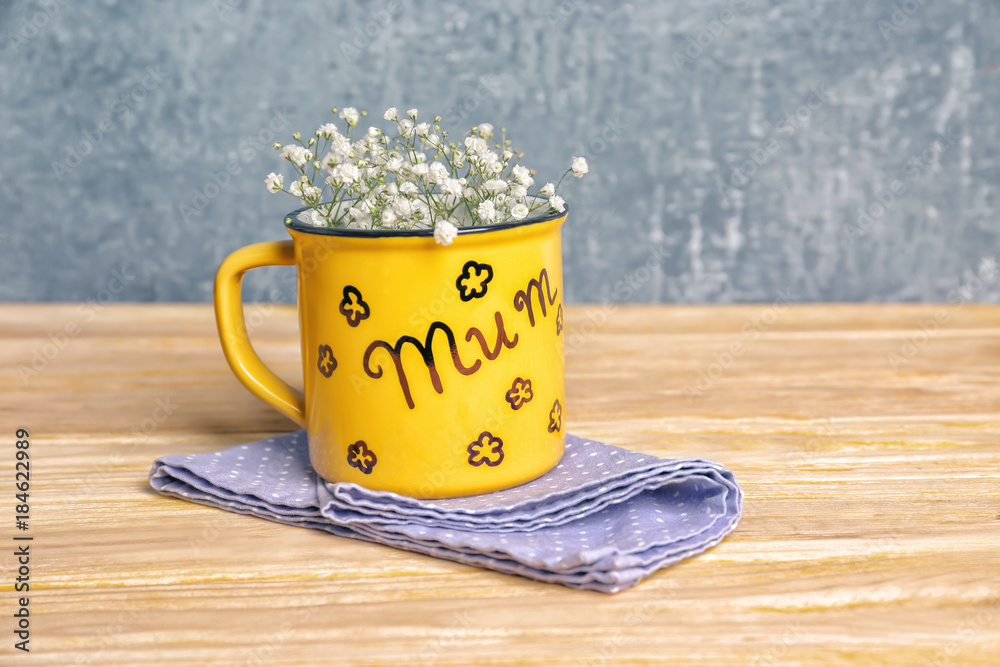 Metal cup with word MUM for Mother's day on table