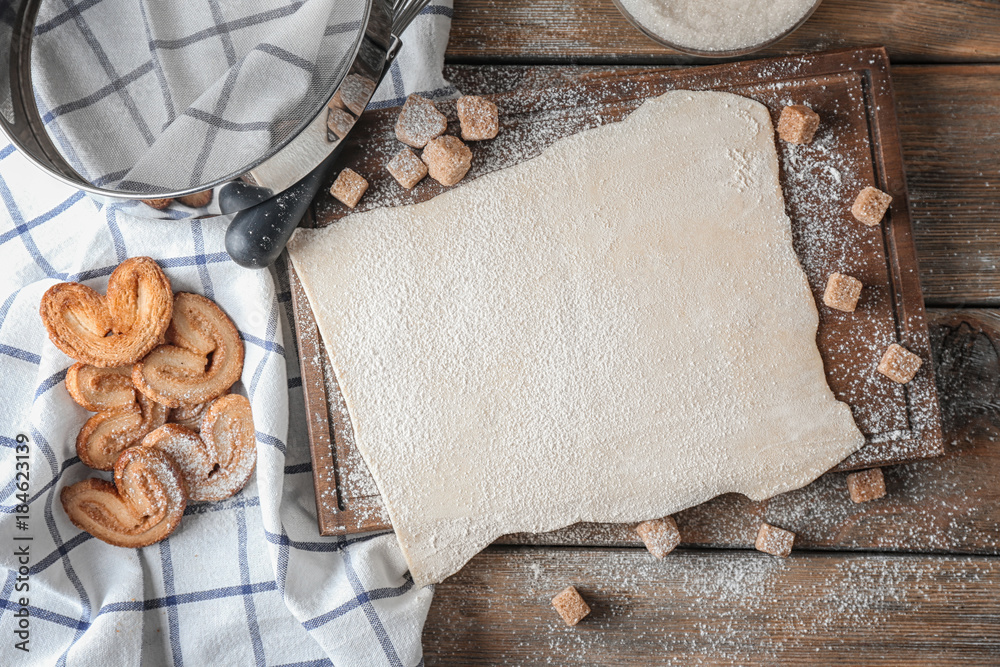 Raw flaky dough and freshly baked cookies on table, top view