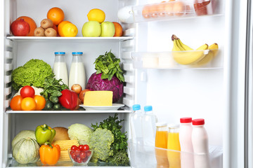 Open fridge full of vegetables and fruits