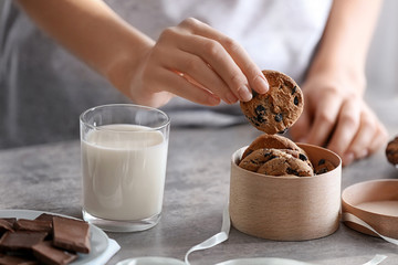 Wall Mural - Woman putting chocolate chip oatmeal cookie into wooden box in kitchen