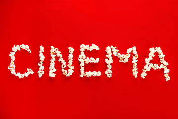 Word CINEMA made of popcorn on color background