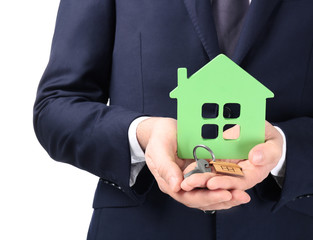 Real estate agent holding house model and key on white background