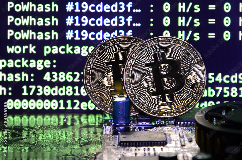 Two bitcoins lies on a videocard surface with background of screen display of cryptocurrency mining by using the GPUs